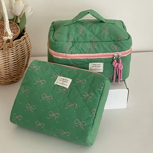Close-up of green quilted makeup bag set with pink bow print and tassel zipper