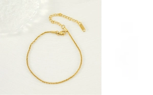 Detail of shimmering gold titanium anklet with lobster clasp and adjustable tail chain