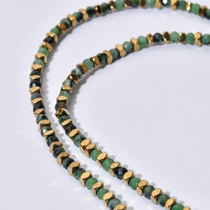 Vue macro de perles de tourmaline verte et d'entretoises en métal doré sur le collier