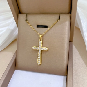 Close-up of gold titanium steel cross necklace with inlaid zircon on champagne jewelry box