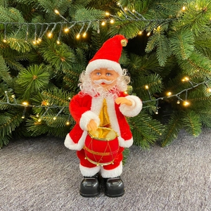 Electric Santa Claus ornament playing a red drum with warm Christmas tree lights behind