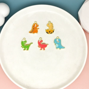 Detail of five colorful enamel dinosaur pendants on a white plate with a colorful background