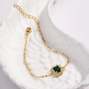 Gros plan détaillé d'un bracelet doré orné d'un zircon vert rectangulaire éclatant