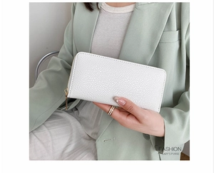 Close-up of a white lychee pattern long leather wallet held by a model in a professional suit