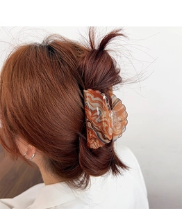 Macro view of amber marble acrylic hair claw clip on model with reddish hair