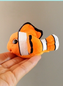 Close-up of a plush clownfish toy with orange and white stripes and soft fabric texture