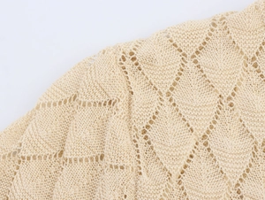 Macro view of beige diamond-patterned openwork knit fabric for summer tops