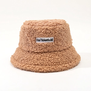 Detail of brown faux shearling bucket hat featuring a white embroidered letter logo patch
