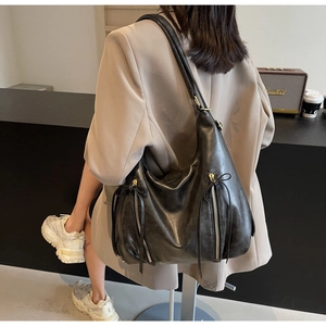 Detail of a large black leather tote bag featuring stylish dual metal zippers and leather bows