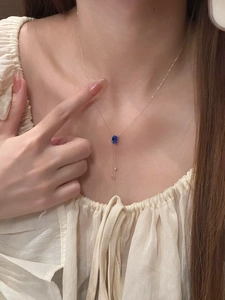 Détail du collier doré avec pendentif en pierre bleue rectangulaire et goutte délicate