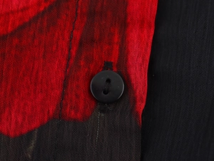 Macro detail of red and black printed chiffon fabric texture with a small black button
