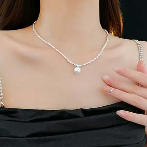Detail of silver-tone necklace featuring a white pearl pendant and shimmering chain