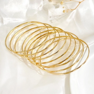 Elegant gold multi-layered bangle set with textured finish on white silk fabric