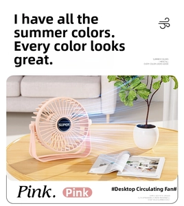 Close-up of a pink portable USB desktop fan with adjustable stand in a cozy living room setting