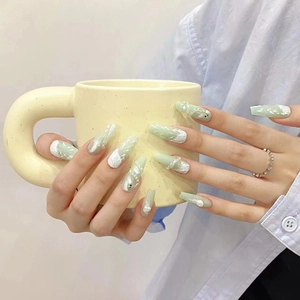 Handmade mint green press-on nails with 3D floral relief and pearl accents on long coffin tips