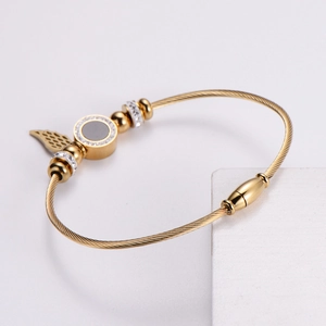 Gold wire bangle with angel wings and crystal circle charms on white stone base