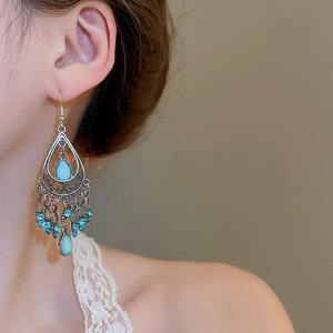 Detailed view of bohemian turquoise waterdrop earrings on model with retro tassels