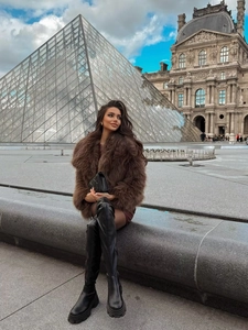 Outdoor street style view of a brown faux fur coat with black leather thigh-high boots