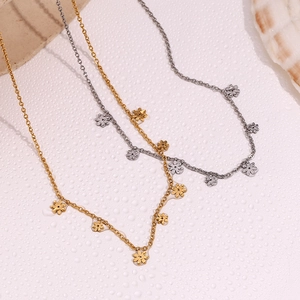 Flat lay of gold and silver small daisy floral necklaces on water drop texture surface