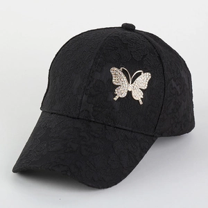 Close-up of black lace baseball cap with shimmering rhinestone butterfly decoration