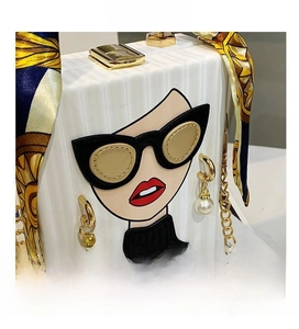 Close-up of white textured box bag with cartoon woman print and 3D pearl earring detail