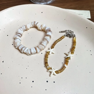 Detailed close-up of shell bead bracelets with starfish charms on a ceramic tray