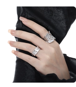 Macro view of silver leaf ring with diamonds and hammered texture wide band on model