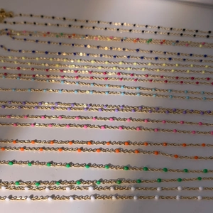 Detail de perles en email colorees sur des colliers bohemiens en acier inoxydable dore