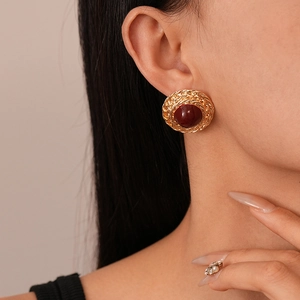 Vintage round gold metal earring with wheat pattern and deep red gemstone on ear