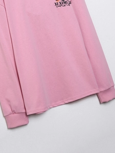 Nahaufnahme der rosa Baumwoll-Stricktextur und der Ärmelnaht dieses lässigen T-Shirts für Damen