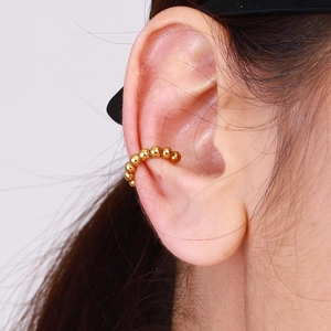 Close-up of a minimalist gold beaded ear cuff clip on the cartilage of a woman's ear