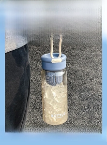 Detail of portable glass bottle with blue handle and tea infuser for cold beverages
