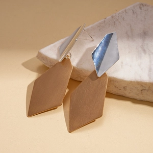 Detailed view of irregular brushed geometric earrings on a natural stone base