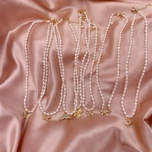 Dettaglio delle collane di perle con vari ciondoli dorati su seta rosa raffinata