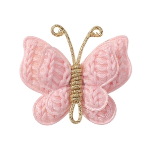Close-up of pink hand-knitted crochet butterfly clip with gold wire-wrapped details