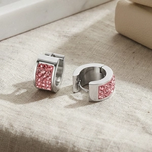 Macro detail of silver stainless steel huggie earrings with pink crystal pavé setting