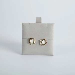 Detail of geometric square stud earrings with gold frame on grey flocking display card