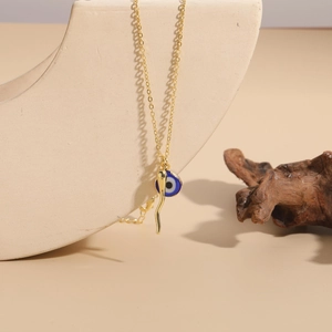 Detail of 14K gold plated evil eye and chili pepper charms on a golden necklace chain