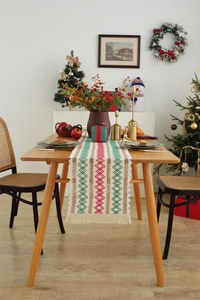 Detail of festive cotton linen table runner with woven geometric patterns and tassels