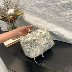 Detail of quilted floral makeup bag with blue begonia print and white bow handle