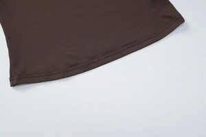 Vue détaillée de l'ourlet du haut marron montrant la couture fine et la texture du tissu