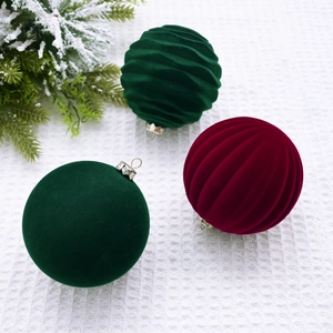 Green and burgundy flocked Christmas balls with diverse textures on white knit background