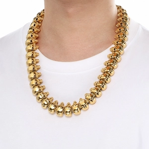 Detailed view of a gold skull link necklace in stainless steel worn on a model's neck