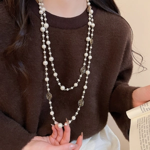 Detail of vintage double-layer pearl necklace with golden rose floral accents on a sweater