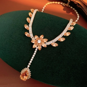 Macro detail of luxury flower necklace with orange zircon drops on green velvet