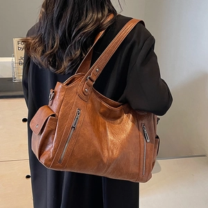 Vintage brown large capacity tote bag with pockets shown on shoulder over black coat