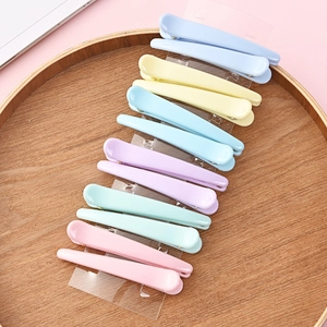 Set of ten colorful plastic hair clips for styling neatly arranged on a round wooden tray