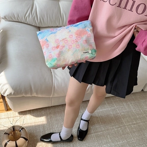 Floral print cotton makeup bag held by model against a minimalist home background