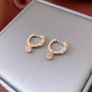 Gros plan de boucles d'oreilles trèfle en zircon doré sur une boîte à bijoux grise