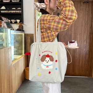 Close-up of fluffy puppy embroidery and PUPPYLAND text on cream canvas tote bag